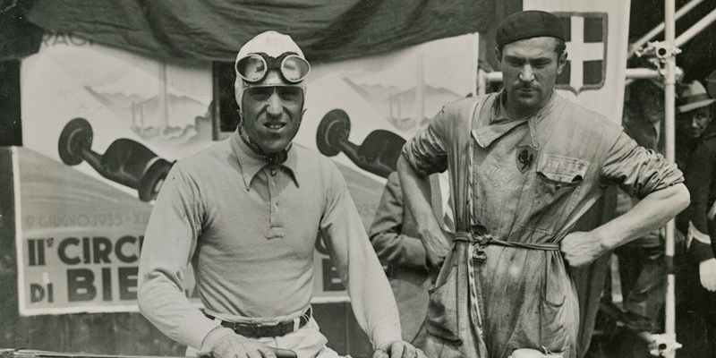 Auguri Tazio Nuvolari. Da sinistra: Nuvolari. Qui insieme a un meccanico della Scuderia Ferrari posano accanto all'Alfa Romeo Tipo B P3 "Sport" in occasione del vittorioso Circuito di Biella 1935